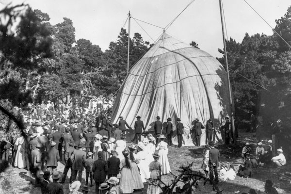 black and white photo with many people standing around a tent