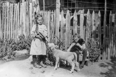 black and white photo of two children with a sheep and a dog